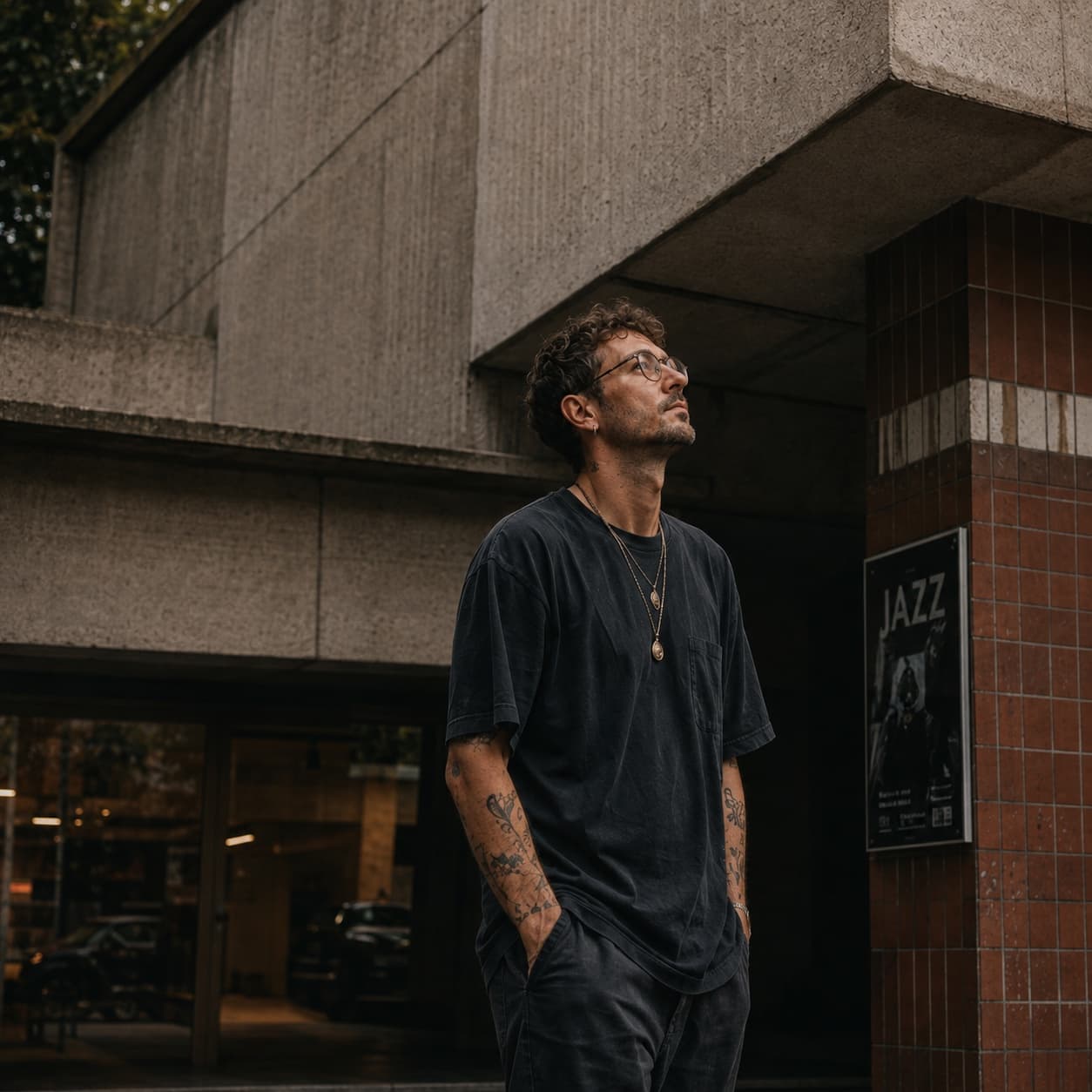 Felix Kïno standing beneath the concrete overhang of a Berlin building, looking upward